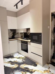 a kitchen with white cabinets and a microwave at Apartament studio in Durleşti