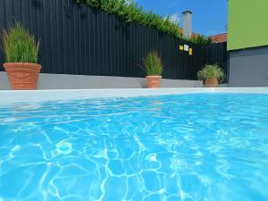 a swimming pool with blue water in front of a fence at Zöld Apartmanház in Balatonboglár