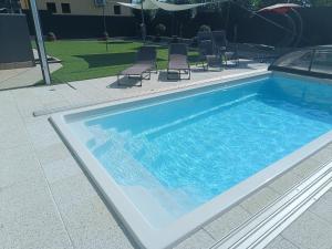 a large swimming pool with chairs next to it at Zöld Apartmanház in Balatonboglár