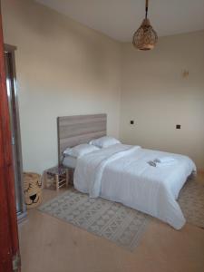 a bedroom with a large bed with white sheets at Tatawi in Ouai Hourri