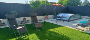 a patio with chairs and an umbrella next to a pool at Zöld Apartmanház in Balatonboglár
