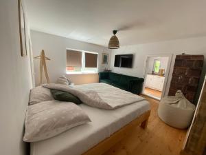 een slaapkamer met een groot bed en een groene bank bij Menasagi Sit & Dream Cottage 2 in Menasag-Ujfalu