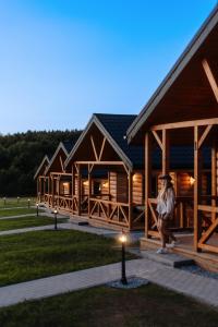 Een vrouw loopt langs een rij houten gebouwen. bij Domki Sudecka Przystań in Duszniki Zdrój