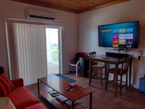 a living room with a table and a large screen television at Cabanya Azul on the Hill with view of the Atlantic in Buckleys