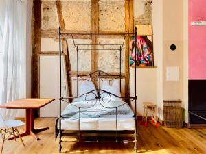 a metal bed in a room with a wooden table at Villa Schloss Rimsingen Fine Apartments in Breisach am Rhein
