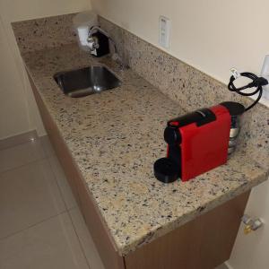 a kitchen counter with a sink and a red appliance at The Sun - Flat in Brasilia