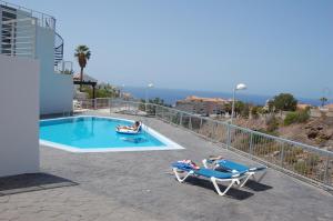 a couple of people laying on chairs next to a swimming pool at Sunset view duplex in Callao Salvaje