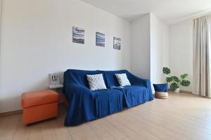 un salon avec un canapé bleu et une chaise orange dans l'établissement IzzHome Oasis, à Pula