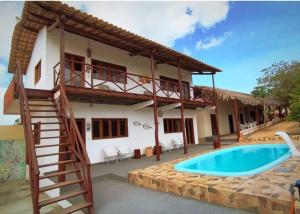 a house with a staircase next to a swimming pool at Pousada Vista Gamboa in Camocim