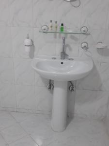 a white sink in a white tiled bathroom at Giza City Hotel-الجيزة سيتى اوتيل in Cairo +61 photos