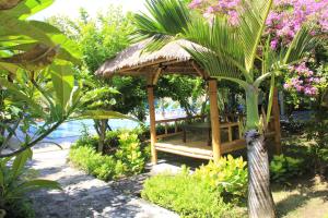 a wooden gazebo with a bench in a garden at Vico hotel in Nusa Dua