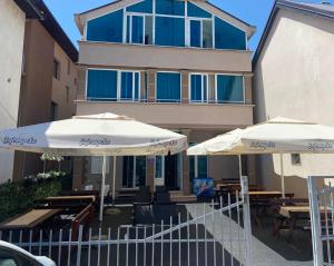two umbrellas and tables in front of a building at Sobe restoran Beba in Pljevlja