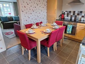 a kitchen with a wooden table and red chairs at Fryers Cottage 3 Bedroom Sleeps 6 Cottage in Scarborough