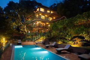 a house with a swimming pool in front of a house at Bamboo Dale Resort & Spa Munnar by Stride in Munnar