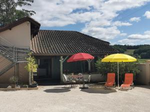 a patio with two umbrellas and a table and chairs at Au cordonnier in Troncens