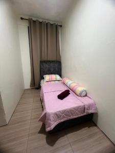 a small bedroom with a bed with a pink blanket at Rizqi Homestay Pasir Mas in Pasir Mas
