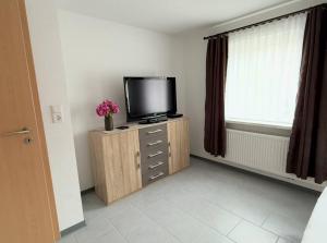 a room with a television on a cabinet with a window at Cosy Holiday Nest in Marienhafe in Marienhafe