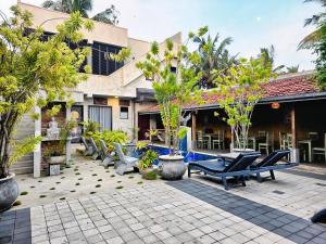 a patio with lounge chairs and trees in front of a building at Chandra Villa in Ambalangoda