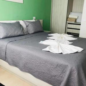 a bed with two white flowers on top of it at Apart Hotel Praia dos Carneiros Apto 101 in Praia dos Carneiros