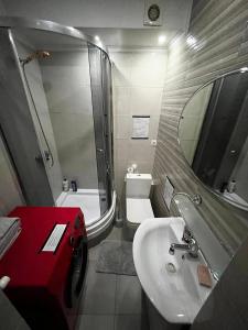 Un baño con lavabo, inodoro y espejo. en Palace Hotel, en Chişinău