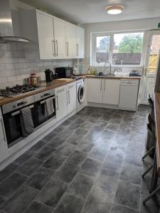 a kitchen with white cabinets and a tile floor at Corby Town Vacations Rooms available for Couples & Singles in Rockingham +7 photos