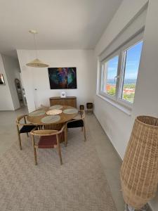 a dining room with a table and chairs and a window at Alma Mare - Modern Apartment with Soul & View in Murter
