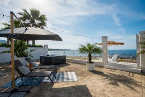 a patio with an umbrella and chairs and the ocean at Natoli Beach House & Villas Villa Manfredi in Molino San Biagio