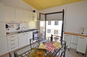 eine kleine Küche mit einem Glastisch und einem Tisch in der Unterkunft Casa Vacanza Tortolì Plus VIII e IX in Tortolì