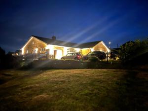 a house with cars parked in a yard at night at The Bungalow by SJP in Northamtonshire