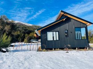 a small house in the snow with a mountain at cabaña kupal in Junín de los Andes