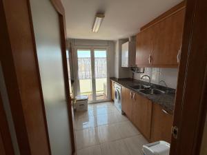 eine Küche mit Holzschränken und einer Spüle in der Unterkunft Atico 3 dormitorios Sant Antoni a 400m de la playa in Sant Antoni de Calonge + 23 Fotos