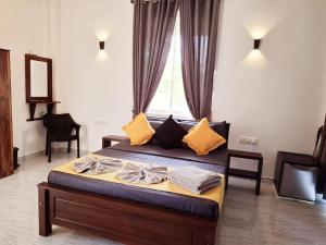 a bedroom with a bed with yellow pillows and a window at Shalom Resorts Yala in Tissamaharama