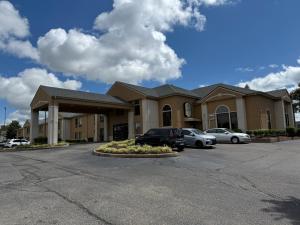 Un edificio con coches aparcados en un estacionamiento. en Hometown Place, en Olive Branch