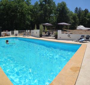 a person swimming in a large blue swimming pool at Dordogne Glamping & Camping in Bouzic