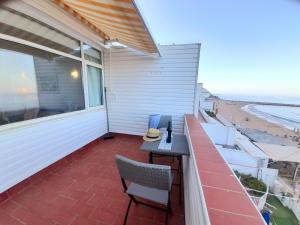 Un balcón con mesa y sillas y la playa. en Sandy Bay Apartment in Both Worlds, for over 50s, Gibraltar, en Gibraltar