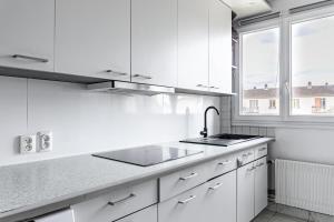 una cucina bianca con lavandino e finestra di Chambre lumineuse et cosy, bord de marne, proche Paris a Neuilly-sur-Marne