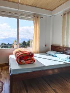 a bedroom with a bed with a large window at Pinescape Homestay in Kurseong