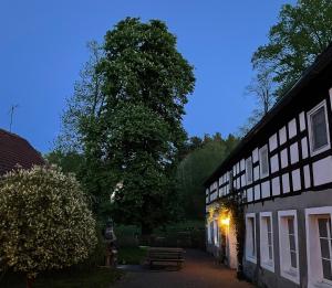 un edificio con un albero e una panchina accanto ad esso di Ferienzimmer Teiselsmühle Gehren Heideblick a Heideblick