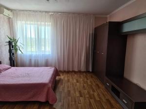 a bedroom with a pink bed and a window at Rohovska appartment in Odesa