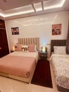 two beds in a bedroom with two lamps at Appartements 7 min Aéroport Marrakech Menara dar Nahila in Marrakesh