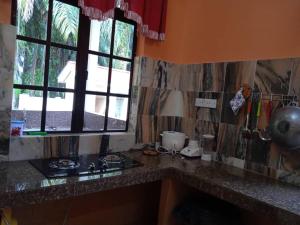 a kitchen counter with a stove and a window at Enalys Homestay untuk orang islam sahaja in Kampung Bota Kiri