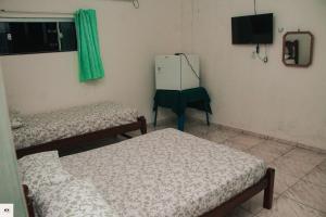 a room with two beds and a tv and a refrigerator at Pousada Fatimar in Salinópolis
