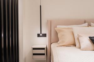 ein Schlafzimmer mit einem Bett mit weißen Kissen und einem Nachttisch in der Unterkunft Monte Smith Luxury Suites in Rhodos (Stadt)
