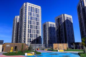 three tall buildings in a city with a playground at Spacious Designer Apartment with a Scenic View in Almaty