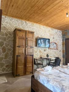 a bedroom with a stone wall with a bed and a table at Jardin miraculeux in Himare