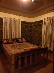 a bed in a room with a stone wall at Lone Tree Creek in Vattavada