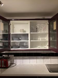 a kitchen cabinet with plates and dishes in it at Large Family Home, Pet Friendly, 4 Bed 2 Bath House, Sleeps 10, Free Wi-Fi, Free Parking in Dagenham Dock