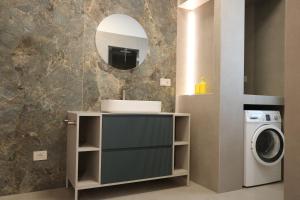 a bathroom with a sink and a washing machine at Villeriunite - Villa Dalia in Baia Verde