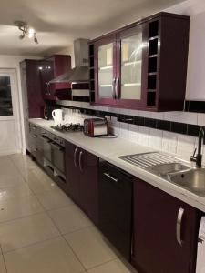 a kitchen with brown cabinets and a sink and a stove at Large Family Home, Pet Friendly, 4 Bed 2 Bath House, Sleeps 10, Free Wi-Fi, Free Parking in Dagenham Dock +13 photos