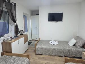 a bedroom with two beds and a tv on the wall at Zolax Apartmans in Mali Iđoš